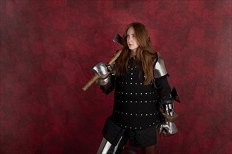 History of the Middle Ages. Portrait of a beautiful medieval female knight in armour on a red background