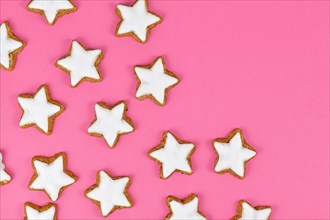 German star shaped glazed cinnamon Christmas cookies called 'Zimtsterne' on pink background
