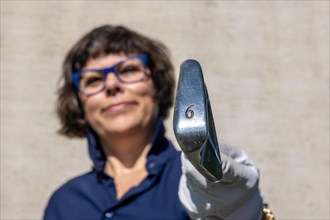Happy Female Golfer with Eyeglasses Holding Up Her 6 Iron Golf Club and Looking at Camera in a Sunny Day in Switzerland
