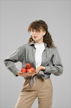 Young woman holds a glass bowl full of apples in hand