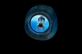 Woman Swimming in the Ship Porthole in Underwater in Swimming Pool in a Sunny Day in Switzerland