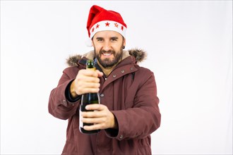 Young very happy Caucasian man with red Christmas hat opening a bottle of champagne on a white background