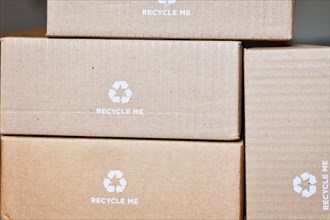 Many cardboard boxes with recycling arrow symbol and text saying Recycle me