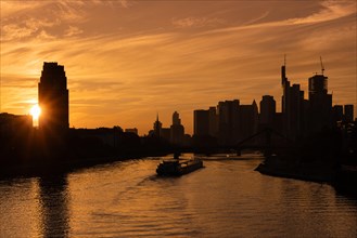 A ship sails towards Frankfurt's banking skyline on the River Main at sunset