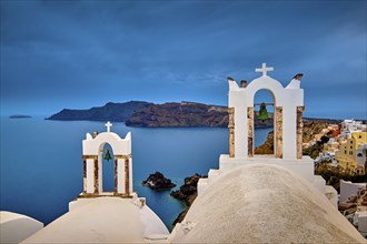 Two bell towers and dome roofs of white Greek Orthodox church in Oia village
