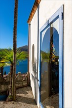 Arabic House and Patio with Palm Tree and Lake Lugano with Mountain and Sunlight in Park Scherrer in Morcote