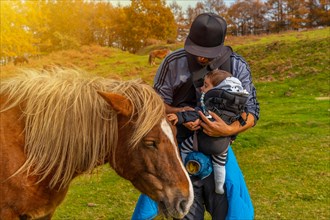 A father and his baby caress a wild horse on Mount Erlaitz in the town of Irun