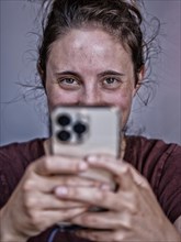 Woman with mischievous smile looks over her mobile phone