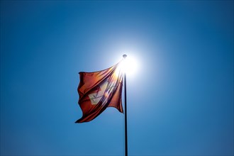 Beautiful Swiss Flag Against Blue Clear Sky and the Sun in a Windy Day in Switzerland