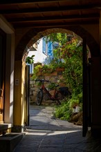 Old Beautiful Street Tunnel with Arch in a Patio and Plants and a Modern Electric Bicycle with Sunlight in Ticino