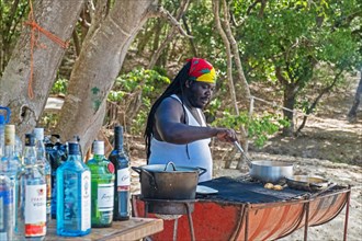 Rastafari cooking meal on barbecue at beach bar at Anse La Roche on Carriacou