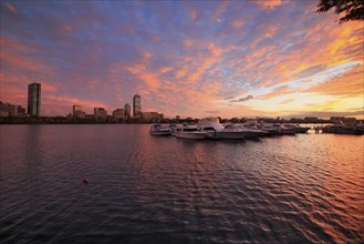 Motorboats on the Charles River and Boston skyline with Hancock Tower at sunset