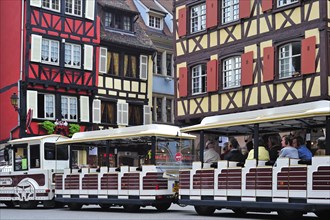 Colorful facades of timber framed houses and sightseeing train with tourists at Colmar