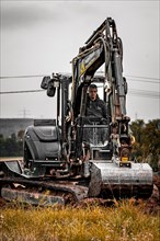Black Yanmar mini tracked excavator during earthworks for house construction on building site