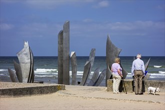 Elderly couple looking at Second World War Two Omaha Beach monument Les Braves at Saint-Laurent-sur-Mer