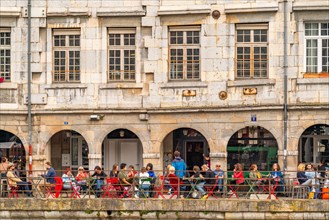 People in the cafe in front of the historic architecture of Quai Vauban on the river Doubs