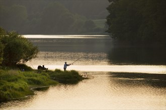 Angler fishing at sunset at the Buetgenbach reservoir in the Hautes Fagnes