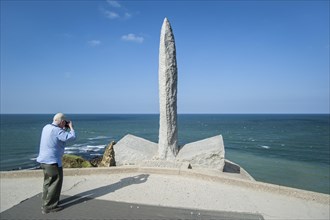 Tourist photographing Second World War Two monument at the Pointe du Hoc cliff overlooking the English Channel