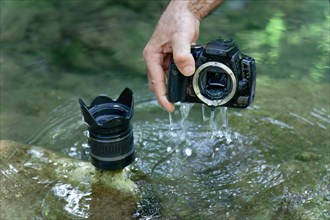 Man pulls his digital camera out of the river that has accidentally fallen into the river flooded from inside
