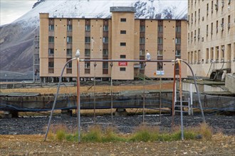 Hotel Tulpan and old swing on children's playground at Pyramiden