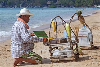 Beach vendor preparing corn on tiny portable barbecue on the island Ko Tao
