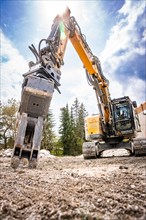 Yellow Liebherr crawler excavator with spreader recycling on demolition site