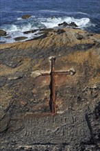 Iron cross embedded in the rock Rocher du Prefet at the coast in Saint-Guenole