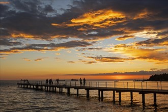 Jetty with tourists silhouetted against sunset over the Adriatic Sea at Ankaran along the Slovenian Riviera