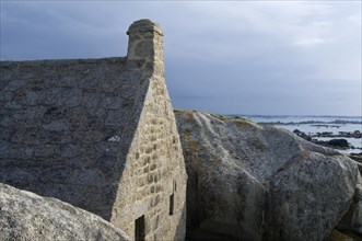 Old customs house wedged between the rocks at Menez Ham