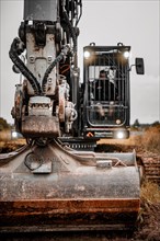 Black Liebherr crawler excavator excavating earth for house construction on building site