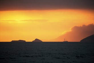 Three-master sailing ship at sunset in front of Santiago Island
