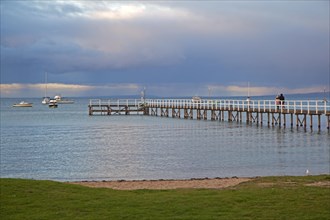 Couple watching sunset from wooden jetty at seaside resort Sorrento in the Port Phillip Bay