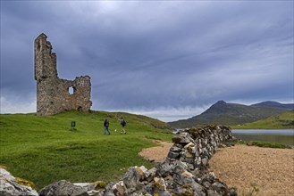 Tourists visiting 16th century Ardvreck Castle ruin at Loch Assynt in the Scottish Highlands
