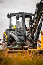 Black Yanmar tracked excavator during earthworks on house construction site