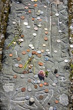 Coins on tombstone marking the grave of Rob Roy MacGregor at the Balquhidder kirkyard