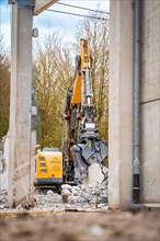 Yellow Liebherr crawler excavator with spreader recycling on demolition site
