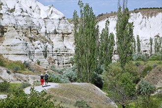 Tourists walking among eroded white sandstone rock formations at Cappadocia in Central Anatolia