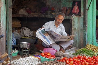 Shopkeeper reading newspaper in grocery shop at Jodhpur