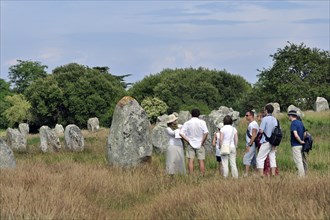 Guide with tourists visiting the Neolithic menhirs