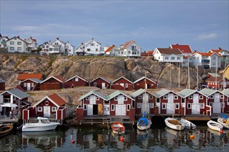 Colourful traditional fishing huts and boathouses along wooden pier at Smoegen