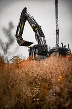 Black Liebherr crawler excavator excavating earth for house construction on building site