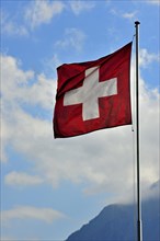 Swiss flag flapping in the wind against cloudy sky