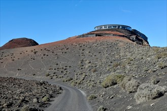 View of volcanic hilltop with tourist centre in Timanfaya National Park with panoramic restaurant El Diablo designed by Cesar Manrique