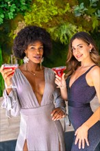 Two friends in gala dresses having a cocktail at a party in a hotel