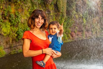 A mother with her son in a red dress at Anjos Waterfall