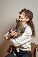 Cute young woman tries to hold her restless cat in her hands
