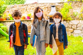 Three brother children with face masks ready for going back to school. New normality