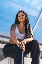 Young woman of black ethnicity with long braids and with tattoos