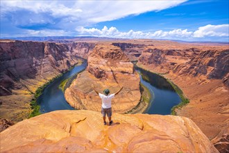 A young man in a white shirt and a green hat at Horseshoe Bend and the Colorado River in the background