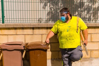 Worker in a recycling factory or clean point and garbage with a face mask and plastic protective screen